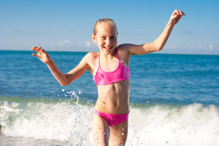 Close-up girl running from sea waveの写真素材