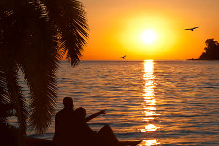 Loving couple watching beautiful sunset on seashoreの写真素材