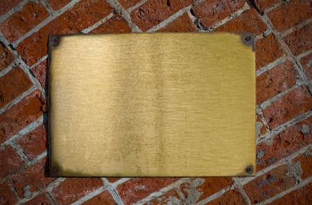 grunge bronze plate with bolts on brick wall backgroundの写真素材