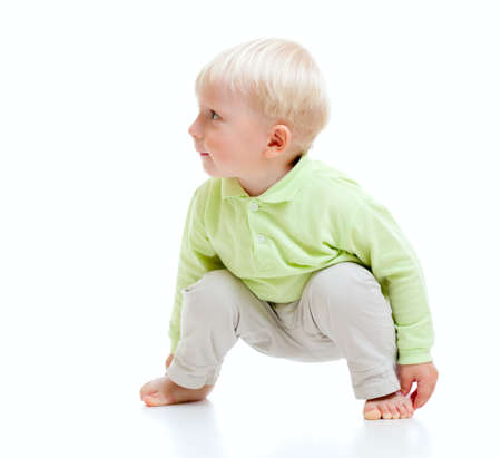 Blond boy barefooted sitting at floor and looking right isolated on whiteの写真素材