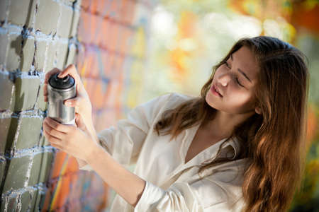 teenage girl portrait with spray can near graffiti wallの写真素材