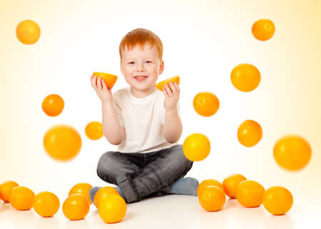 redheaded boy with falling orangesの写真素材