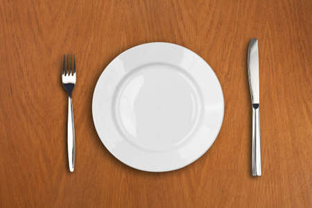 round white plate, knife and fork on wooden table