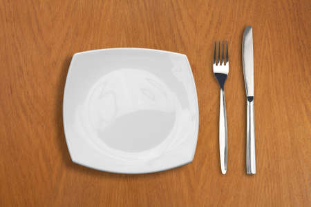 square white plate, knife and fork on wooden table