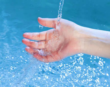 kid's hand under stream of waterの写真素材