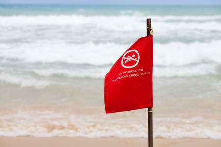 no swimming here dangerous strong current warning flag on beachの写真素材