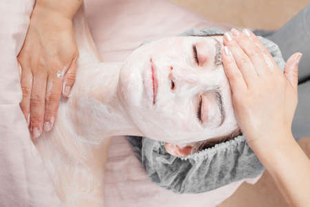 Beautiful woman with clear skin getting beauty treatment of her face at salonの写真素材