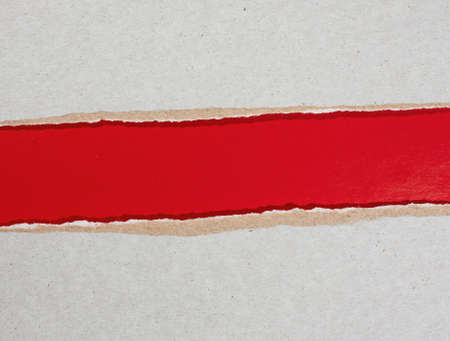 torn cardboard over red paperの写真素材