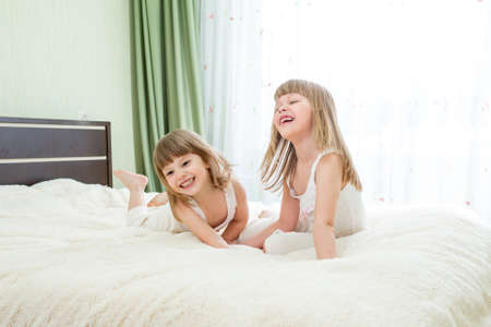 Two little girls lying on bedの写真素材