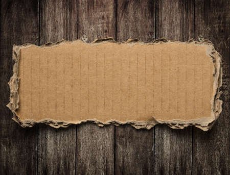 Torn cardboard on wood backgroundの写真素材