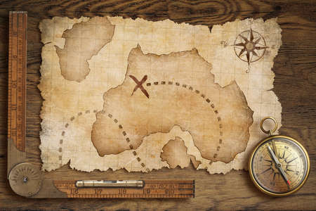 aged treasure map, ruler and old bronze compass on wooden table top viewの写真素材