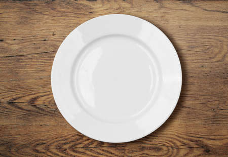 white empty dinner plate on wooden table surfaceの写真素材