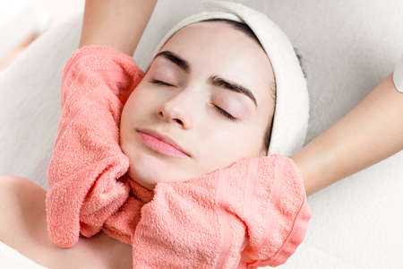 Young woman facial treatment or massage with towelの写真素材