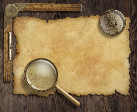 vintage nautical compass and loupe on table with treasure mapの写真素材