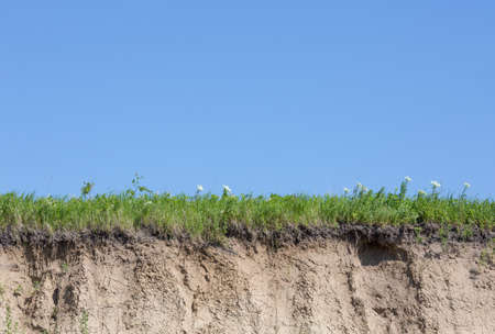 Ravine or gully cut with soil, grass and blue skyの写真素材