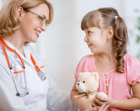 Pediatrician doctor talking with kid in officeの写真素材