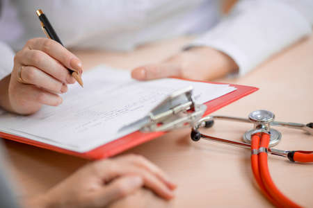 Doctor making some notes about patientの写真素材