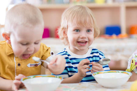 smiling little kid eating in kindergartenの写真素材