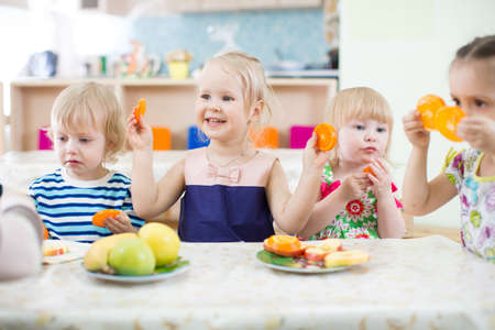 Funny kids eating fruits in kindergartenの写真素材