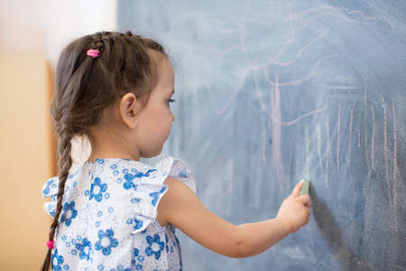 Cute little girl side view near blackboardの写真素材