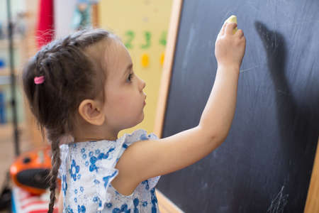 Cute little girl side view near blackboardの写真素材