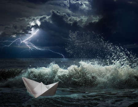 small paper boat in ocean storm with lgihting and wavesの写真素材