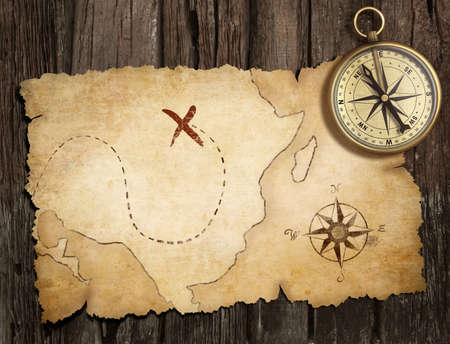 aged brass antique nautical compass on table with old treasure mの写真素材