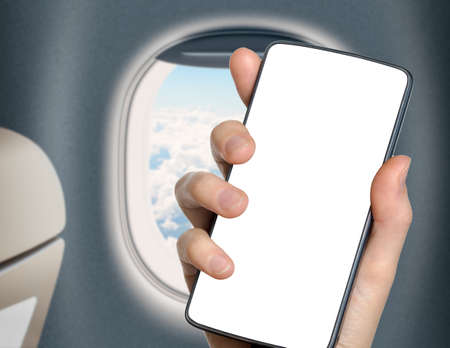 hand with blank mobile phone in airplane or jet interiorの写真素材