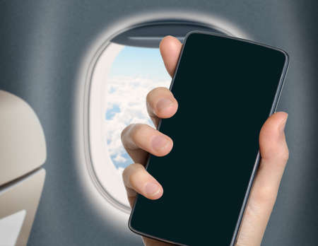 hand with blank mobile phone in airplane or jet interiorの写真素材