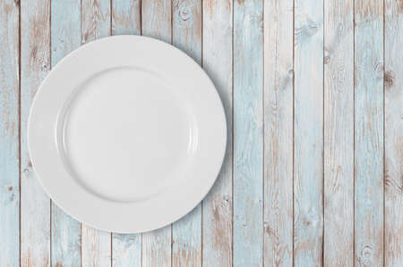 white empty dinner plate on left side of blue wooden tableの写真素材