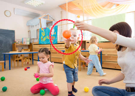 Happy children playing with ball and ring in kindergartenの写真素材