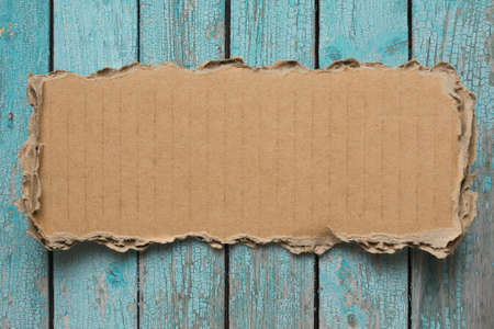 Rip cardboard piece on blue vintage wood backgroundの写真素材