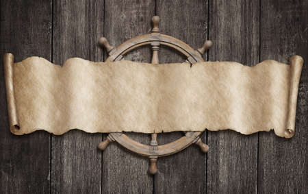 Old pirates map scroll and steering-wheel over wood background. Mixed media.の写真素材