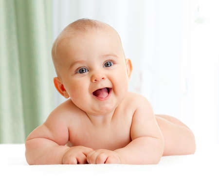 Adorable baby boy lying in light green bedroomの写真素材