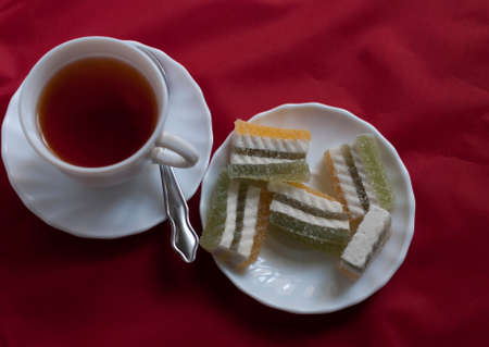 hibiscus tea and a plate of multi-colored jelly on a red fabric backgroundの写真素材
