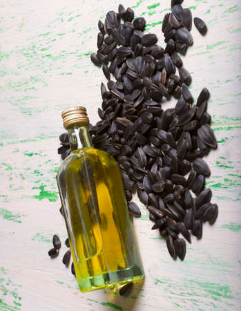 small bottle of oil and sunflower seeds on wooden backgroundの写真素材