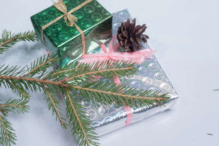 Wrapped in paper Christmas gifts and green fir branch on a light background