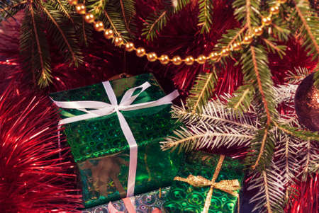 Green gift box under Christmas tree branches. Wrapped in green paper gift box Toned image