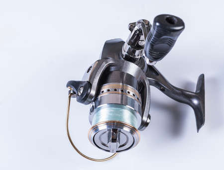Fishing gear on white background. Silver coil, spools of fishing line