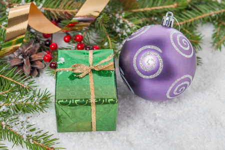 Green gift box and Christmas balls on the snow among the branchesの写真素材
