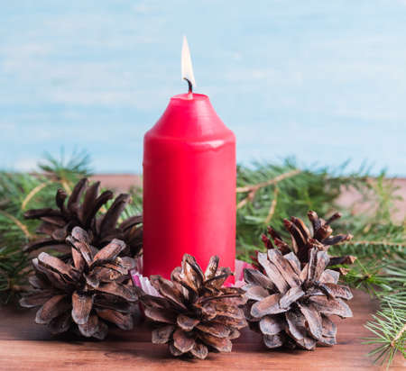 New Year background from a candle surrounded by fir conesの写真素材