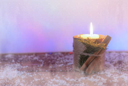 mandarins and a candle on a snow-covered surface under a snowfallの写真素材