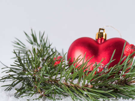 Red Christmas tree toy in the shape of heart and fir branch on a white backgroundの写真素材