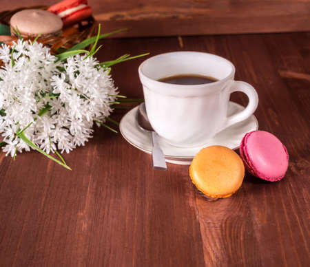 Cup of coffee, cakes on the table and white flowers on the backgroundの写真素材