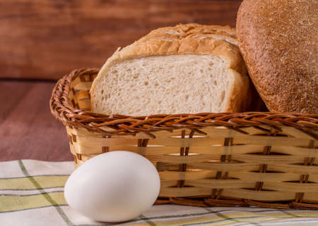 Basket with bread standing on a napkin on a wooden backgroundの写真素材