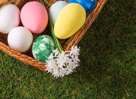 Wooden basket with Easter eggs on the grass field. The concept of the Easter, spring and traditional...