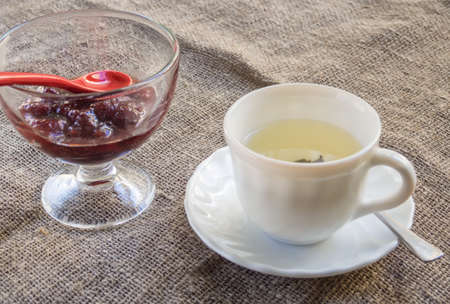 Cup with green tea and jam on the tableの写真素材