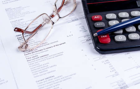 calculator with blue pen and glasses on financial statements