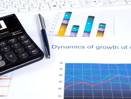 Financial charts and tables on the desktop. Calculator pen