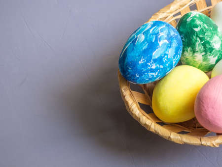 Easter eggs in a basket and white flowers in a dark blue background